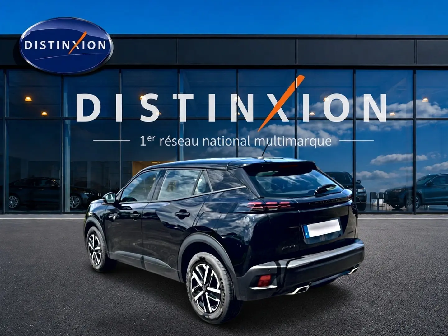 Vue 3/4 arrière droite d’un Peugeot 2008 noir 2025 avec becquet et feux arrière LED devant une vitrine Distinxion.