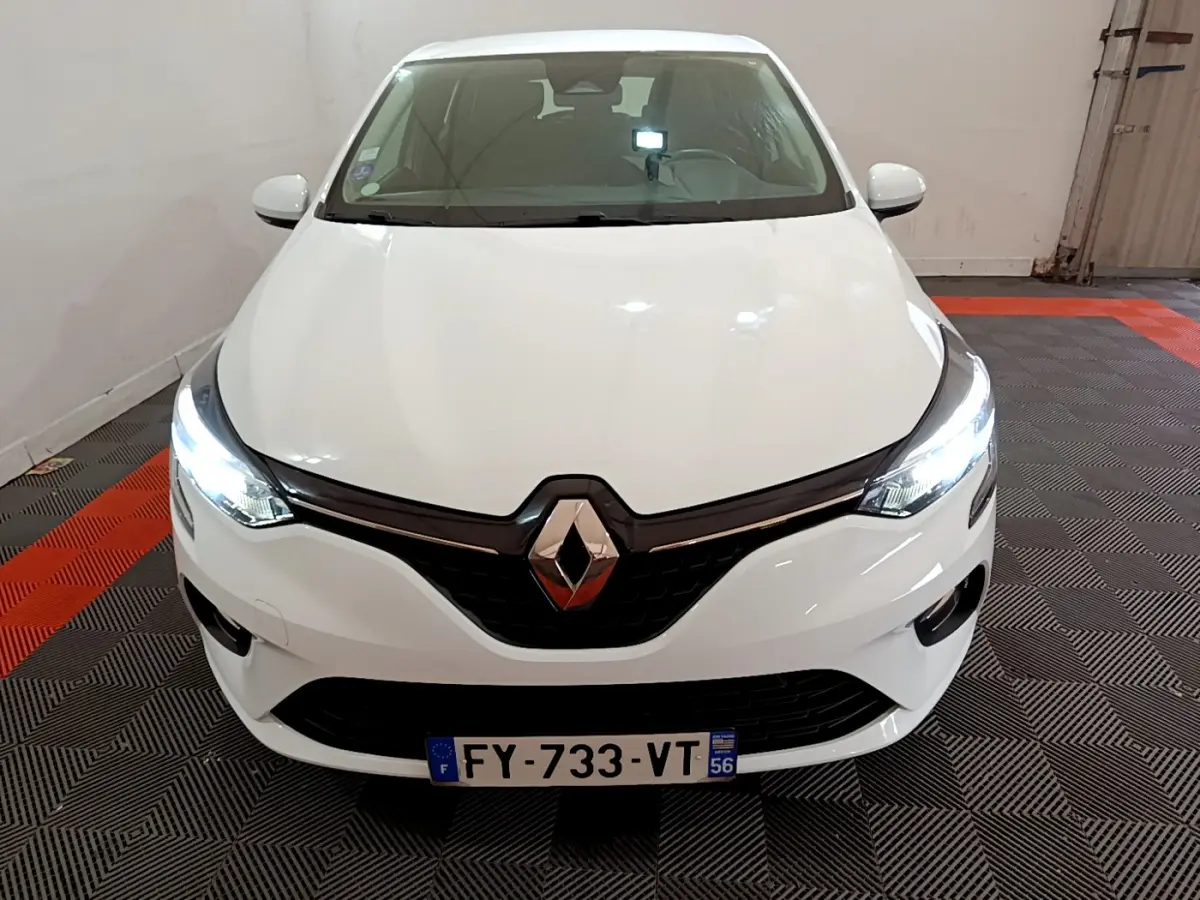 Vue frontale d'une Renault Clio Business blanche avec phares LED allumés dans un garage.