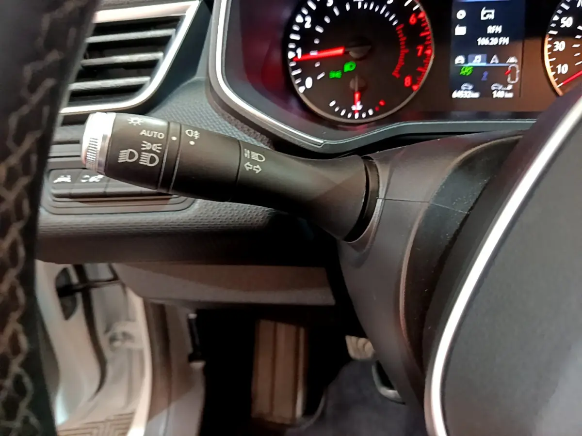 Gros plan sur la manette des phares et clignotants du tableau de bord d'une Renault Clio Business blanche de 2021.