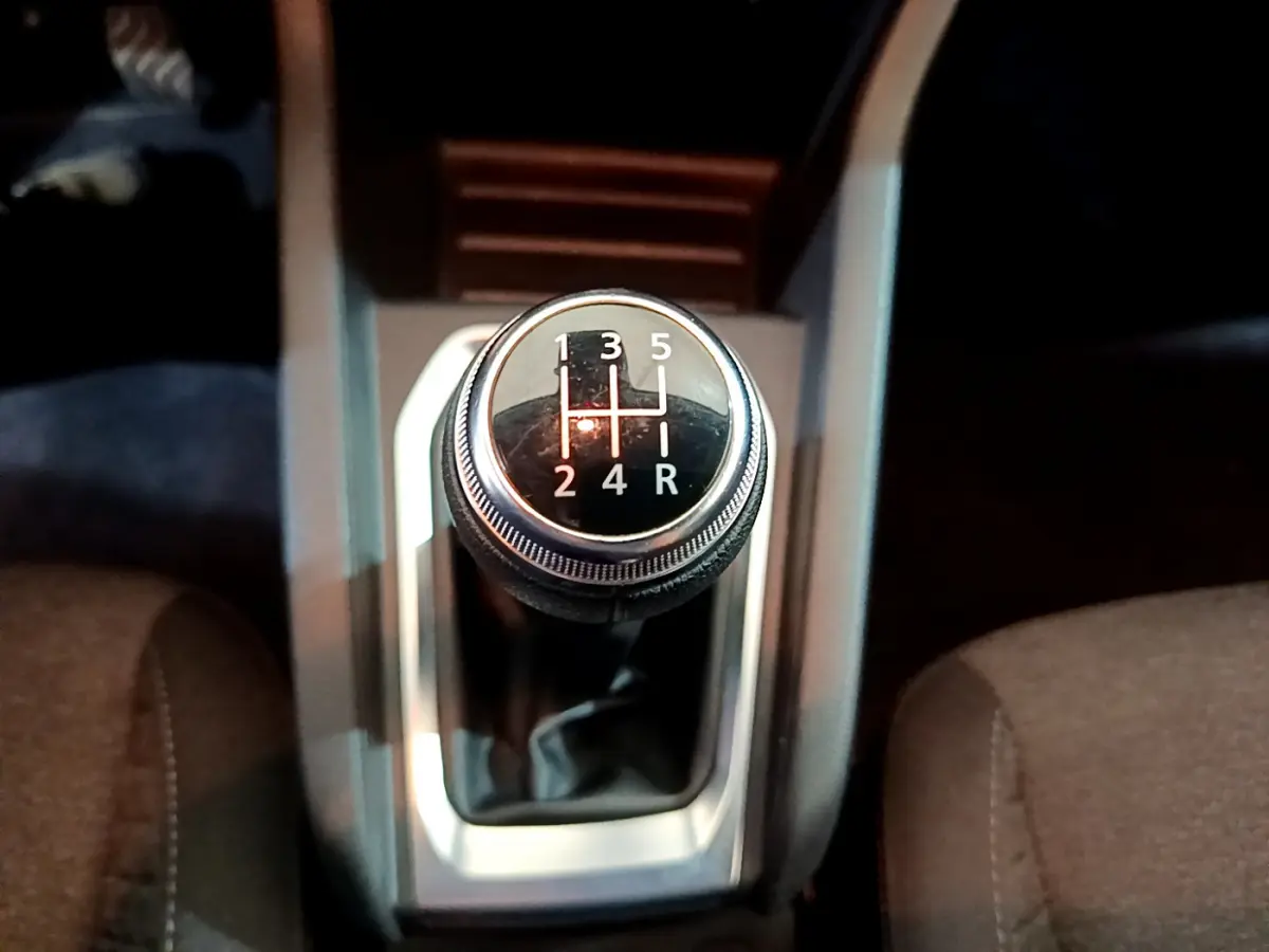 Gros plan sur le levier de vitesses manuel noir de la Renault Clio Business blanche, entouré des sièges avant.