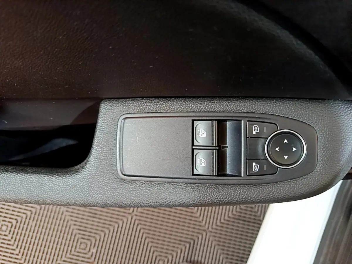 Gros plan sur les commandes de lève-vitres et réglages des rétroviseurs côté conducteur d'une Renault Clio blanche 2021.