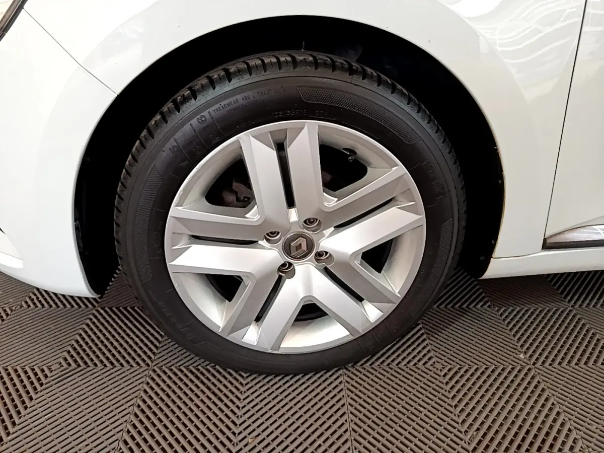 Gros plan sur la roue avant droite de la Renault Clio Business blanche, mettant en valeur la jante alliage au design moderne.