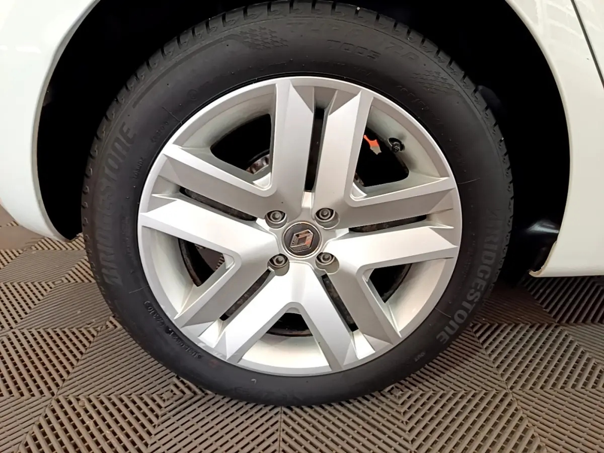 Gros plan sur la roue avant droite blanche d'une Renault Clio Business SCe 65 avec jante alliage et logo Renault central.