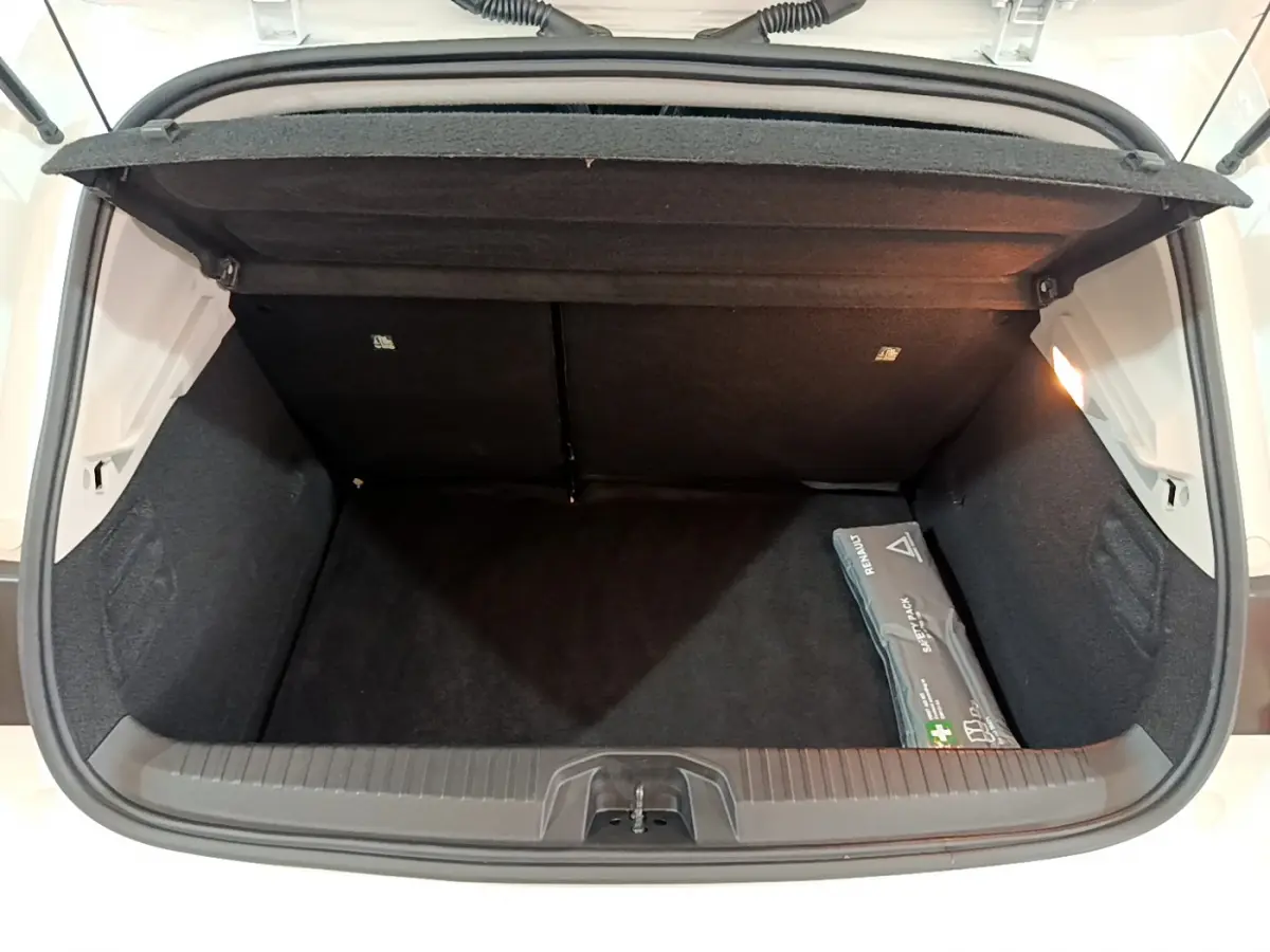 Coffre ouvert vu de dessus de la Renault Clio Business blanc, avec trousse de secours visible à droite.