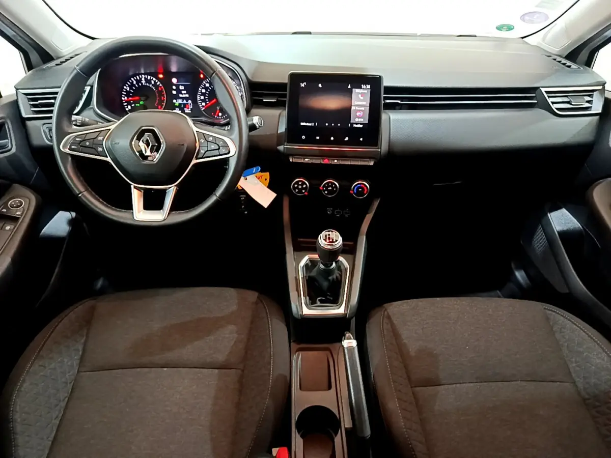 Intérieur de Renault Clio Business blanc 2021, vue frontale sur tableau de bord, volant cuir et écran tactile central.