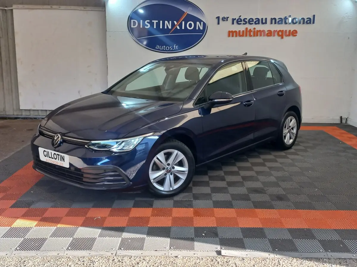 Volkswagen Golf bleu 2022 vue 3/4 avant droit, avec jantes alliage et calandre moderne dans showroom.