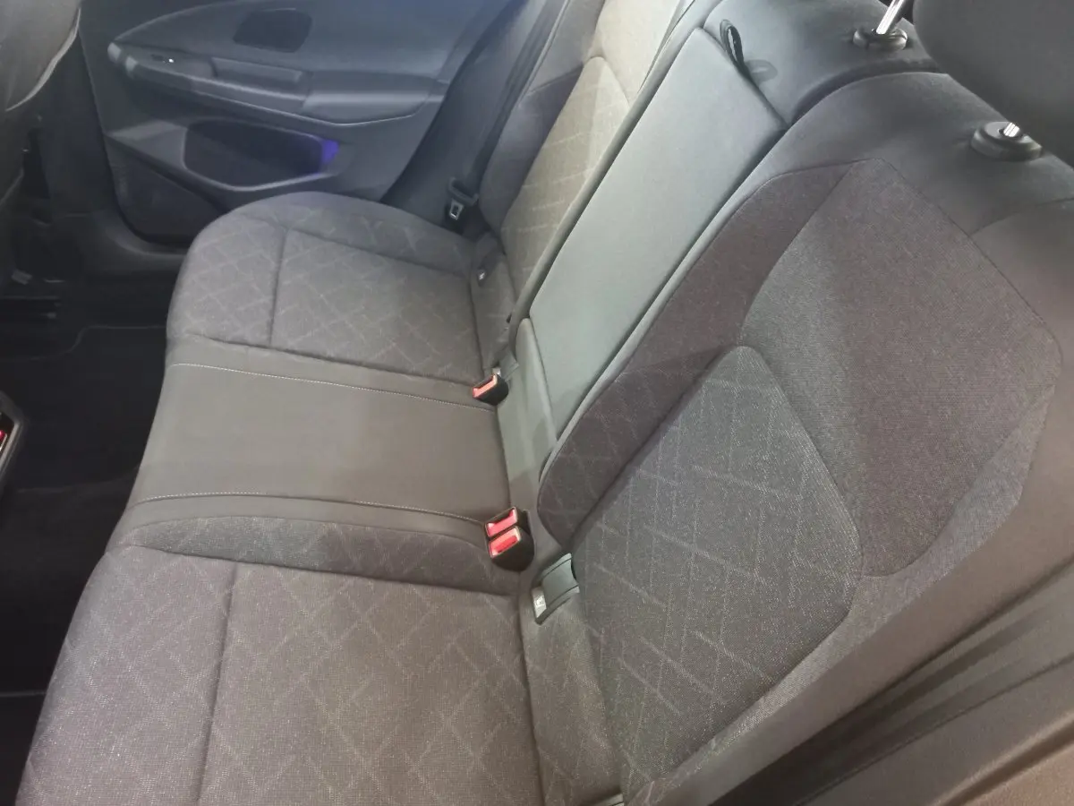 Vue intérieure côté droit des sièges arrière gris foncé de la Volkswagen Golf 1.5 ETSI 2022 avec ceinture rouge.