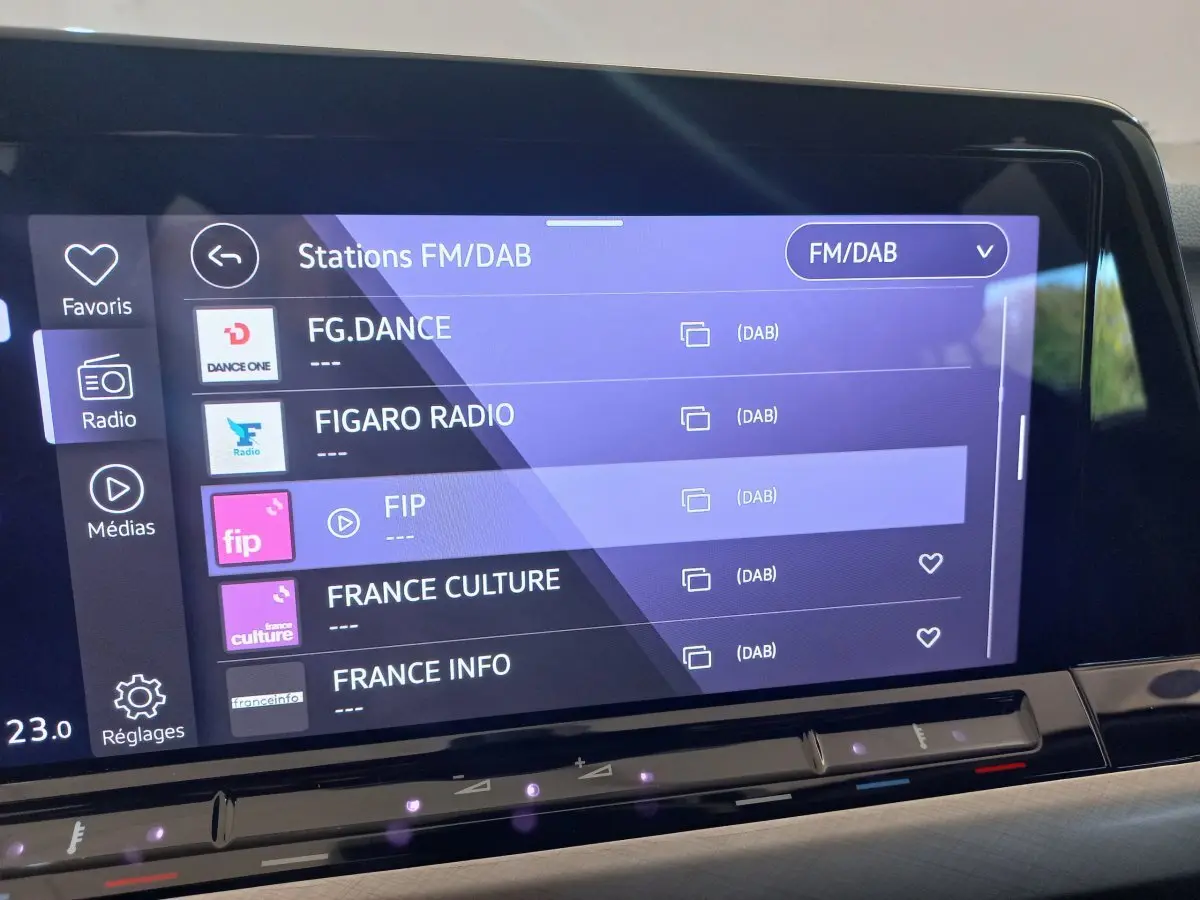 Écran tactile central de la Volkswagen Golf 1.5 bleu, affichant les stations radio FM/DAB en intérieur.