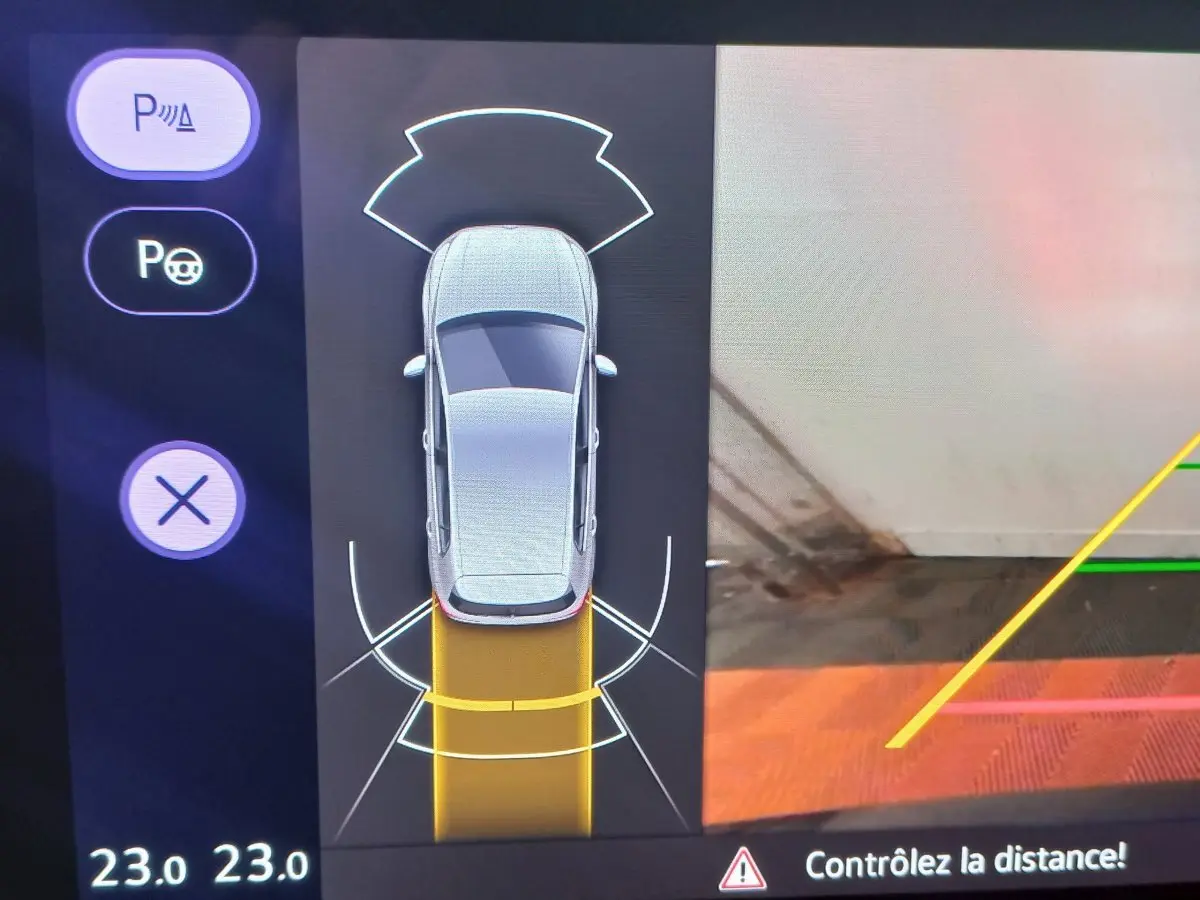 Affichage caméra de recul avec vue aérienne de la Volkswagen Golf bleue en stationnement, guidage jaune visible.