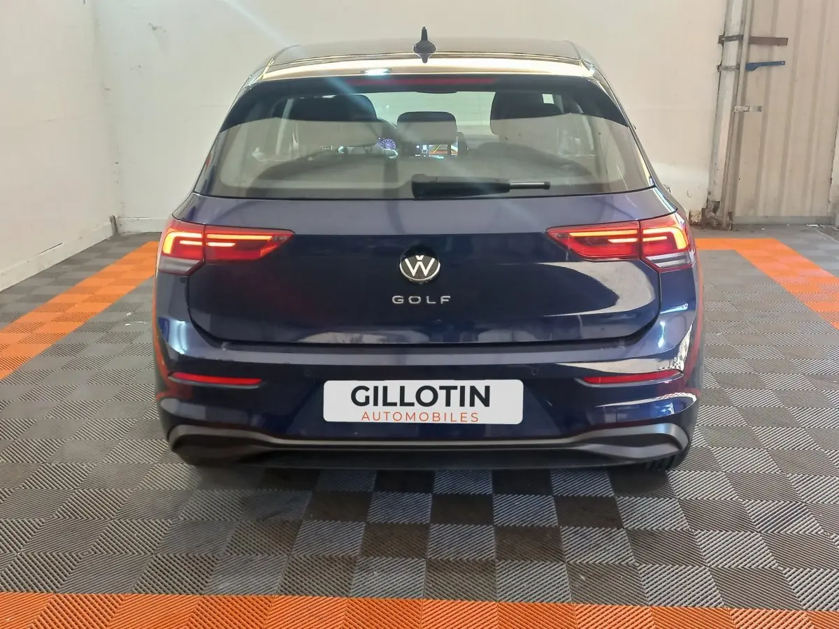 Vue arrière d'une Volkswagen Golf bleu foncé avec feux arrière LED allumés dans un garage.
