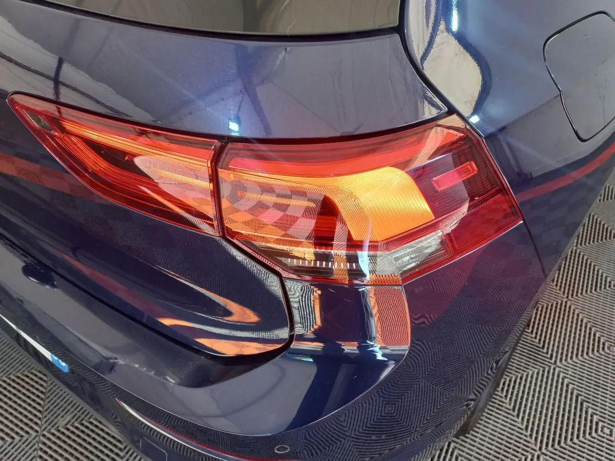 Gros plan sur le feu arrière droit d'une Volkswagen Golf bleue 2022, soulignant la teinte profonde et les lignes nettes.