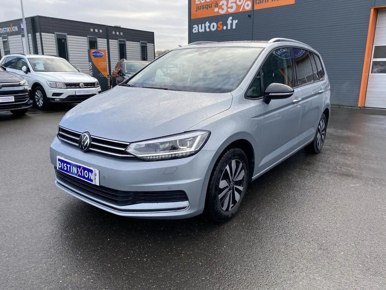 Volkswagen Touran 2025 Oyster argent métallisé en 3/4 avant droit, avec projecteurs IQ.Light et jantes distinctives.