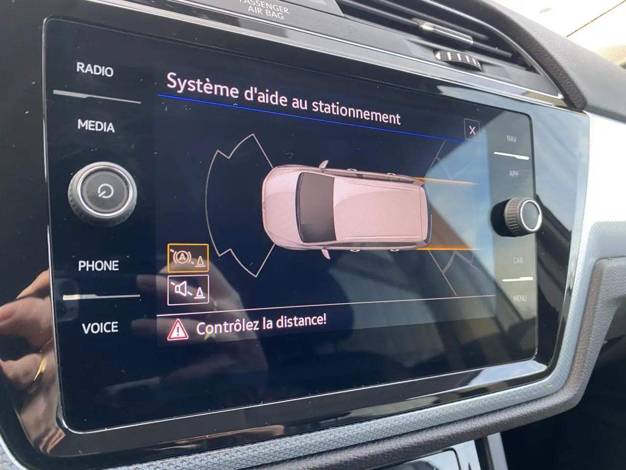 Écran tactile intérieur du Volkswagen Touran 2025 affichant le système d'aide au stationnement en vue de dessus du véhicule.