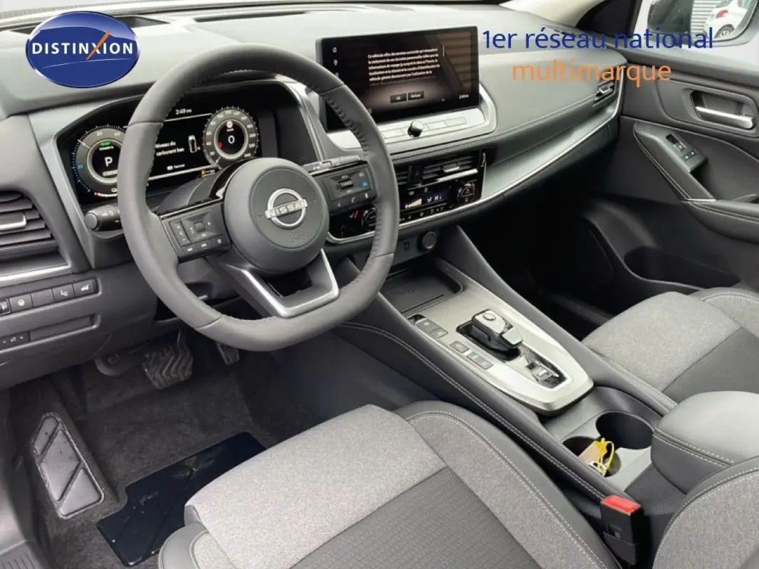 Vue intérieure côté conducteur du Nissan Qashqai 2025 gris, avec volant cuir multifonctions et écran tactile central.