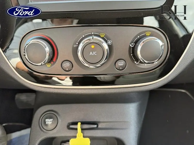 Gros plan sur la commande de climatisation noire brillante du Renault Captur gris platine, avec boutons ronds et affichage A/C allumé.