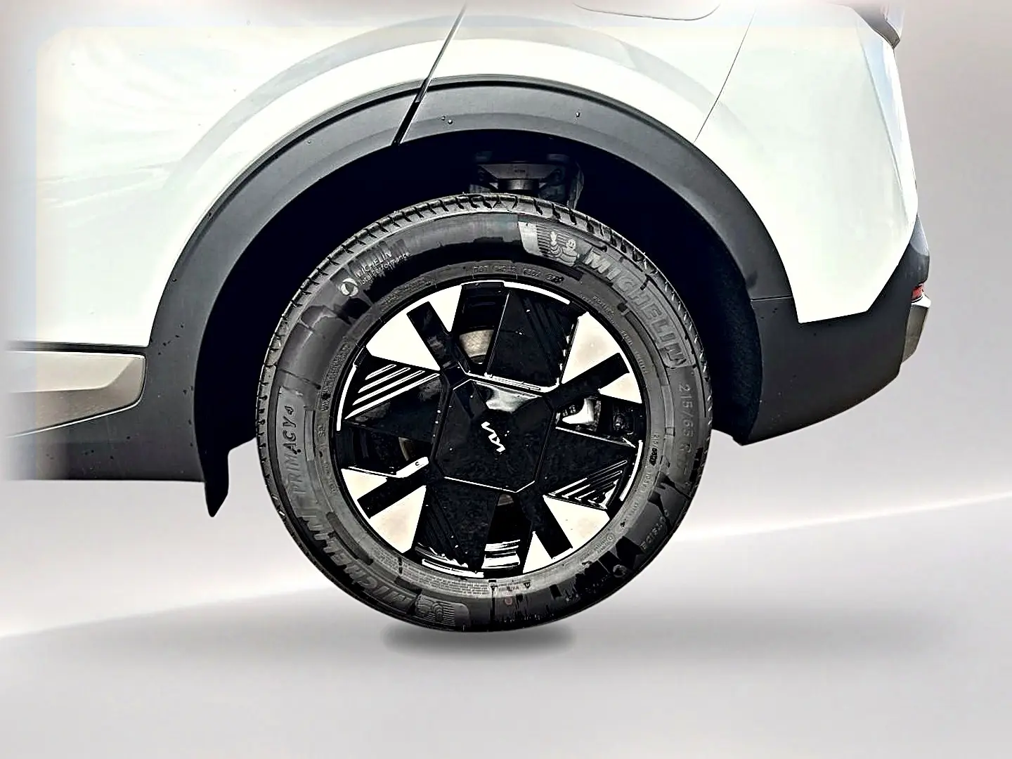 Gros plan sur la roue arrière droite blanche du Kia Sportage 1.6 hybride 239 avec jante alu noire et détails modernes.