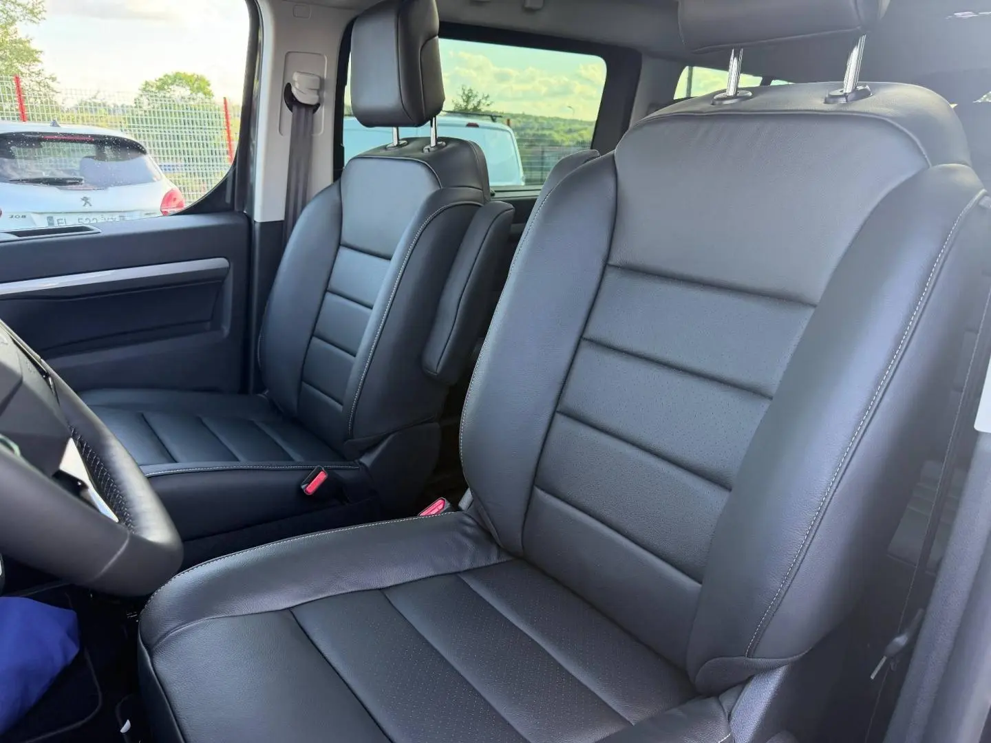 Vue intérieure rapprochée des sièges avant en cuir noir du Citroën Spacetourer XL gris titane, avec accoudoir central côté passager.