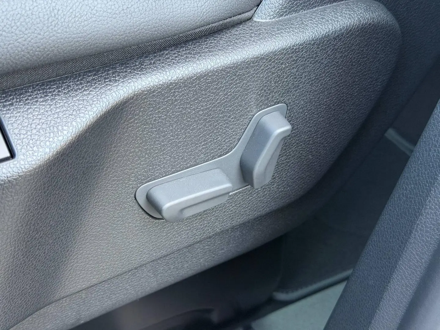 Détail des commandes de réglage manuel du siège avant en plastique gris dans un Citroën Spacetourer XL gris Titane.