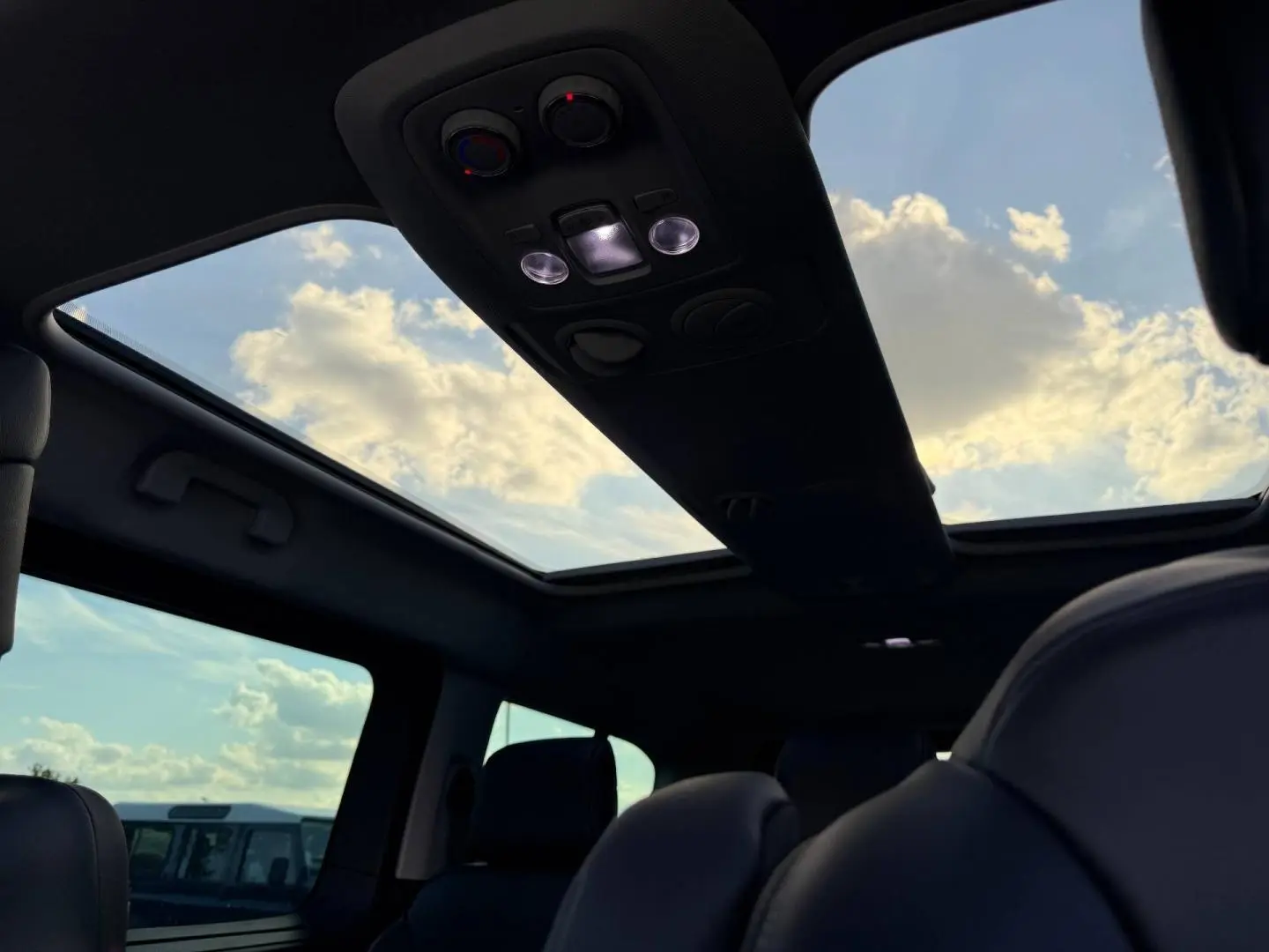 Vue intérieure du toit ouvrant panoramique du Citroën Spacetourer XL gris titane avec ciel nuageux visible.