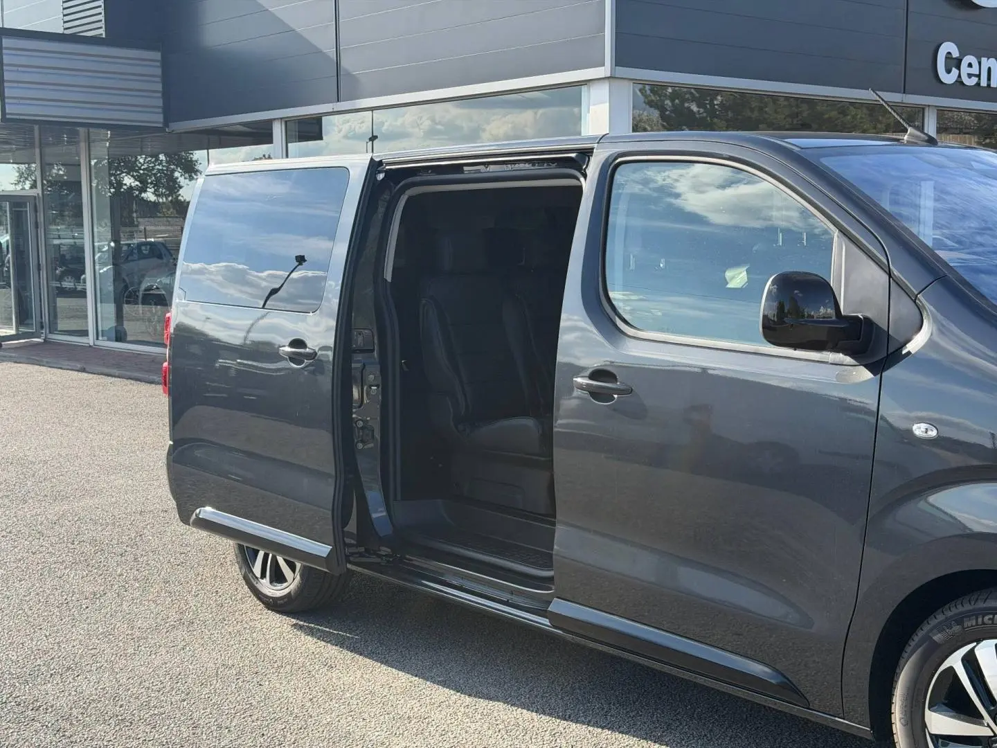 Vue latérale droite d’un Citroën Spacetourer XL gris titane avec porte coulissante ouverte dévoilant l’intérieur noir.