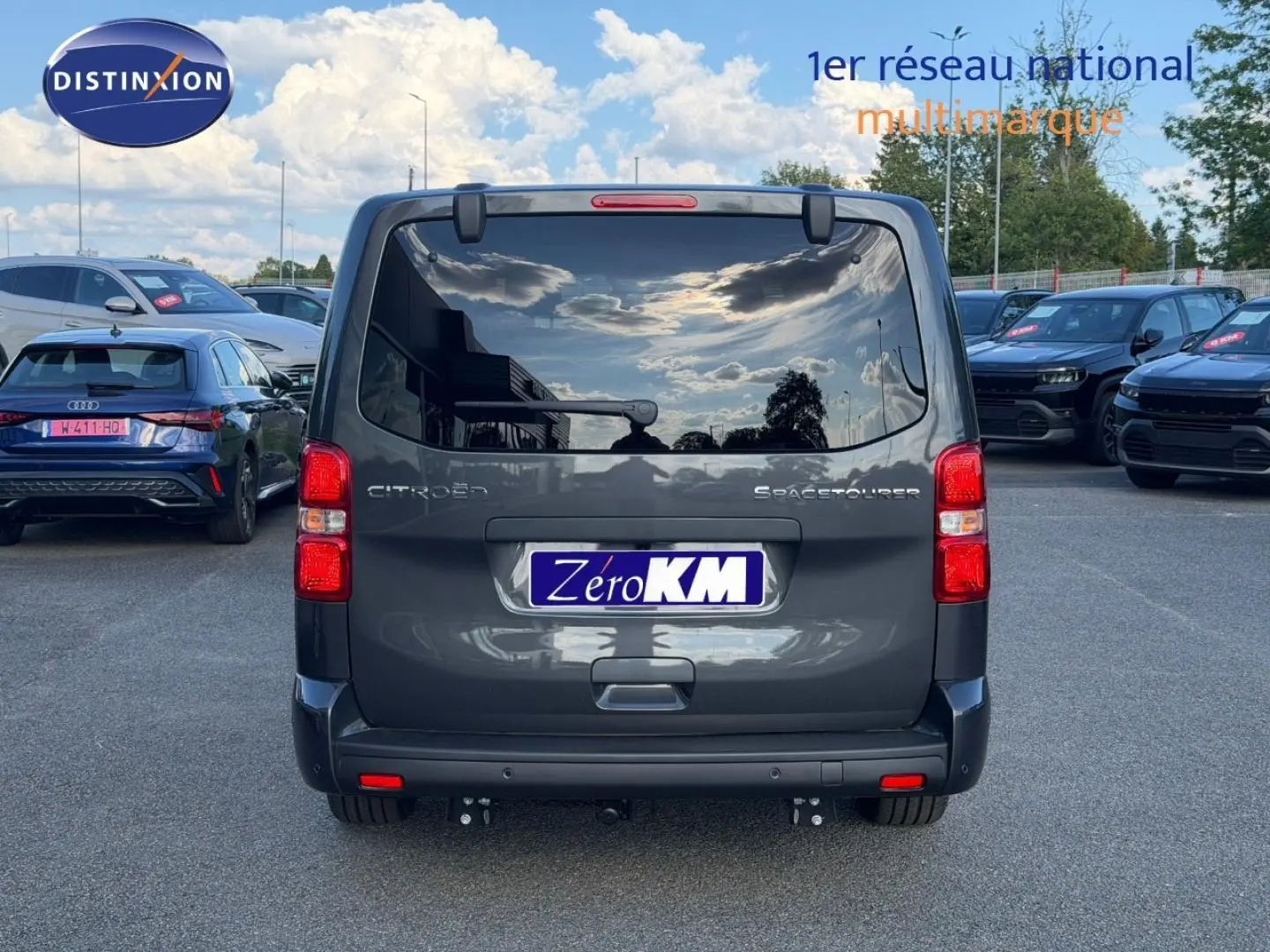 Vue arrière d'un Citroën Spacetourer XL gris titane avec vitres arrière surteintées et hayon fermé sur parking.