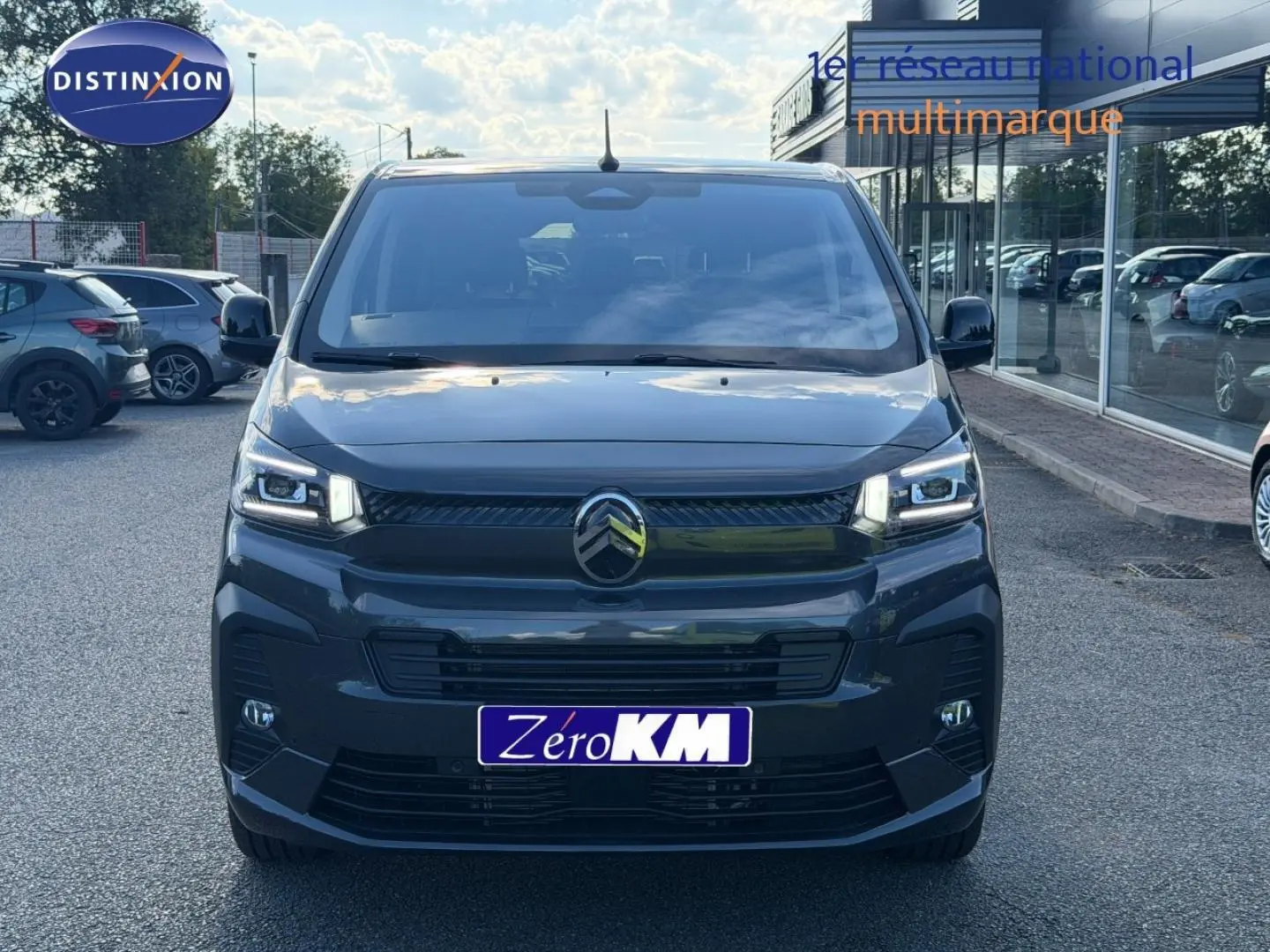 Vue avant d'un Citroën Spacetourer XL gris titane avec phares LED allumés sur parking extérieur.