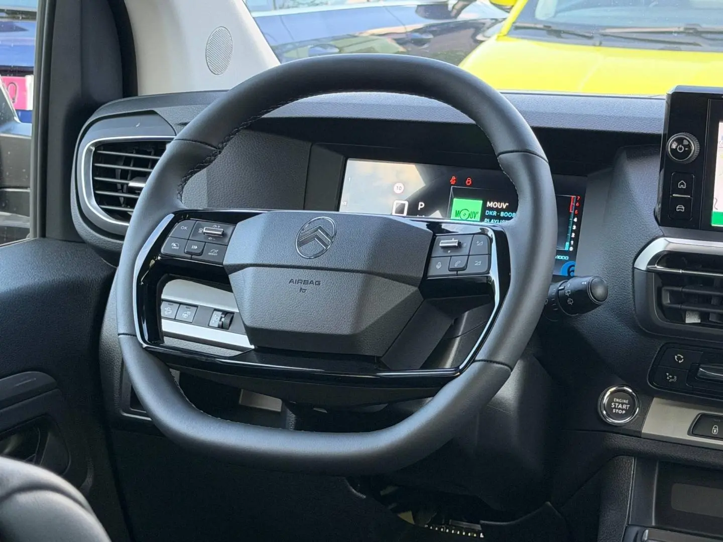 Vue intérieure centrée sur le volant noir du Citroën Spacetourer XL 2026 avec tableau de bord numérique en arrière-plan.