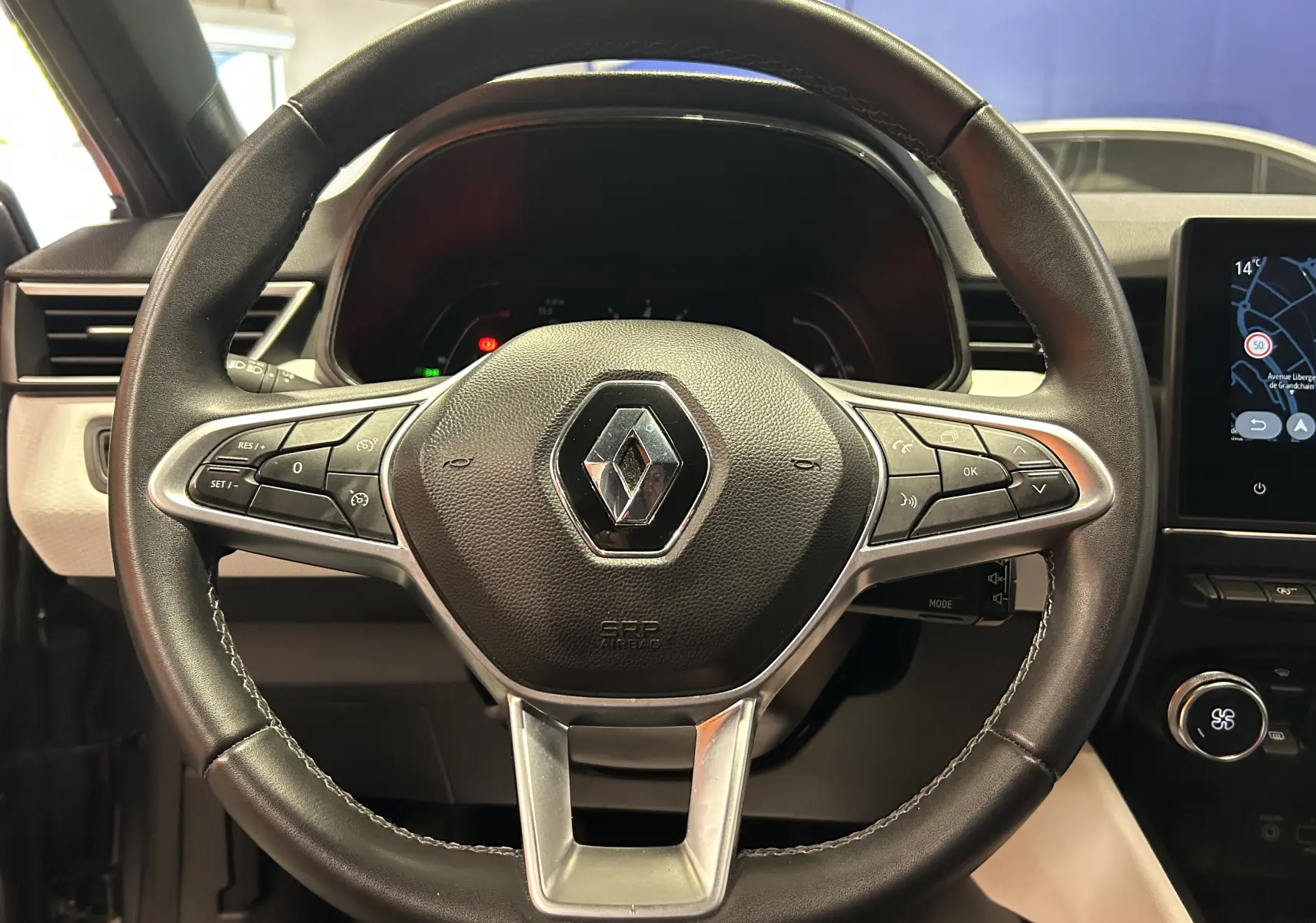 Volant en cuir avec commandes intégrées et logo Renault au centre, intérieur moderne de la Clio V gris 2023.