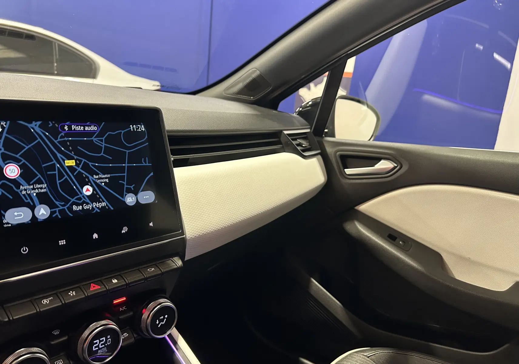 Intérieur avant droit de Renault Clio V TCe 90 TECHNO 2023 avec tableau de bord noir et blanc et écran tactile GPS allumé.