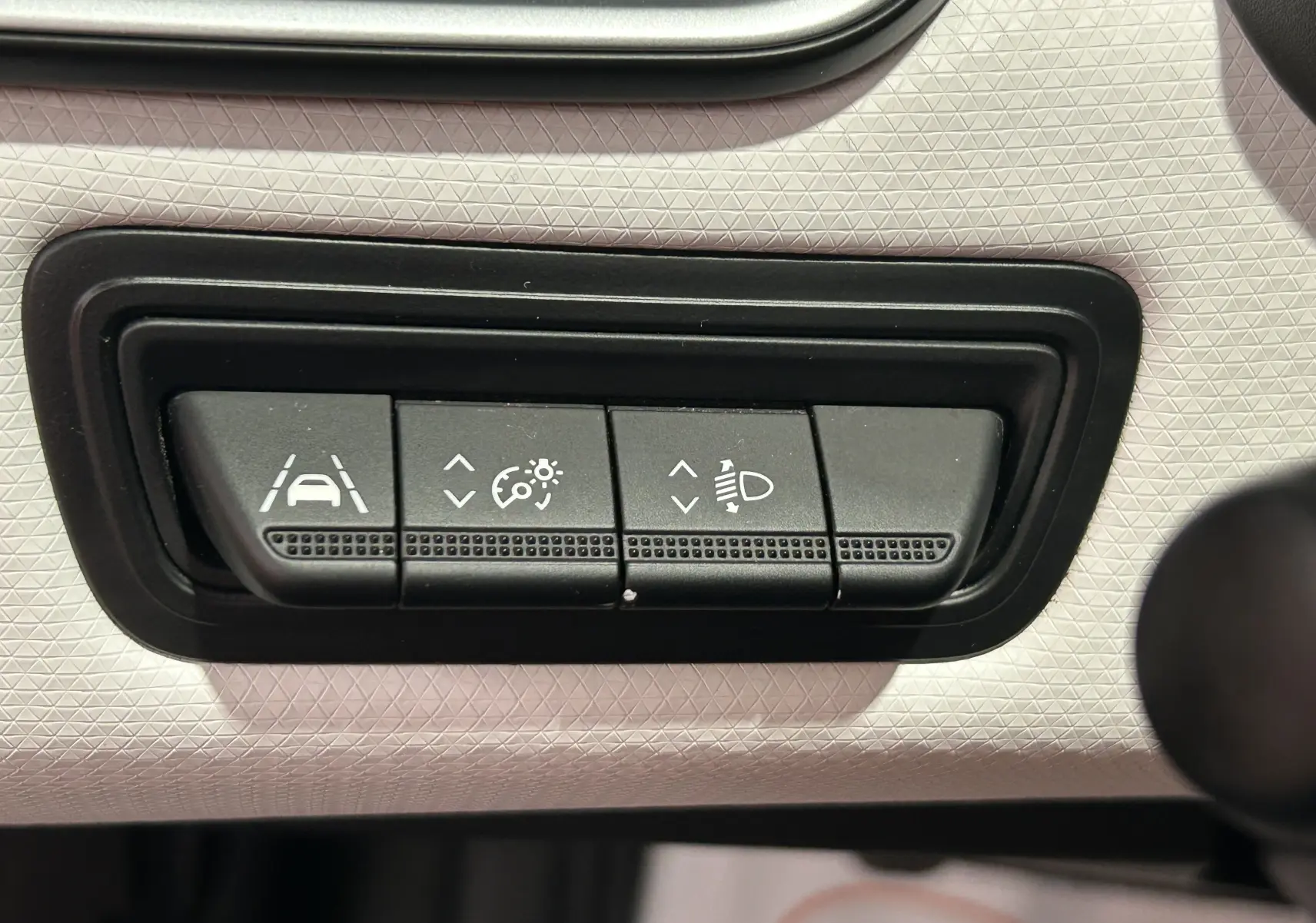 Boutons de réglage de l'aide à la conduite et des phares sur le tableau de bord gris clair d'une Renault Clio V TCe 90 TECHNO 2023.