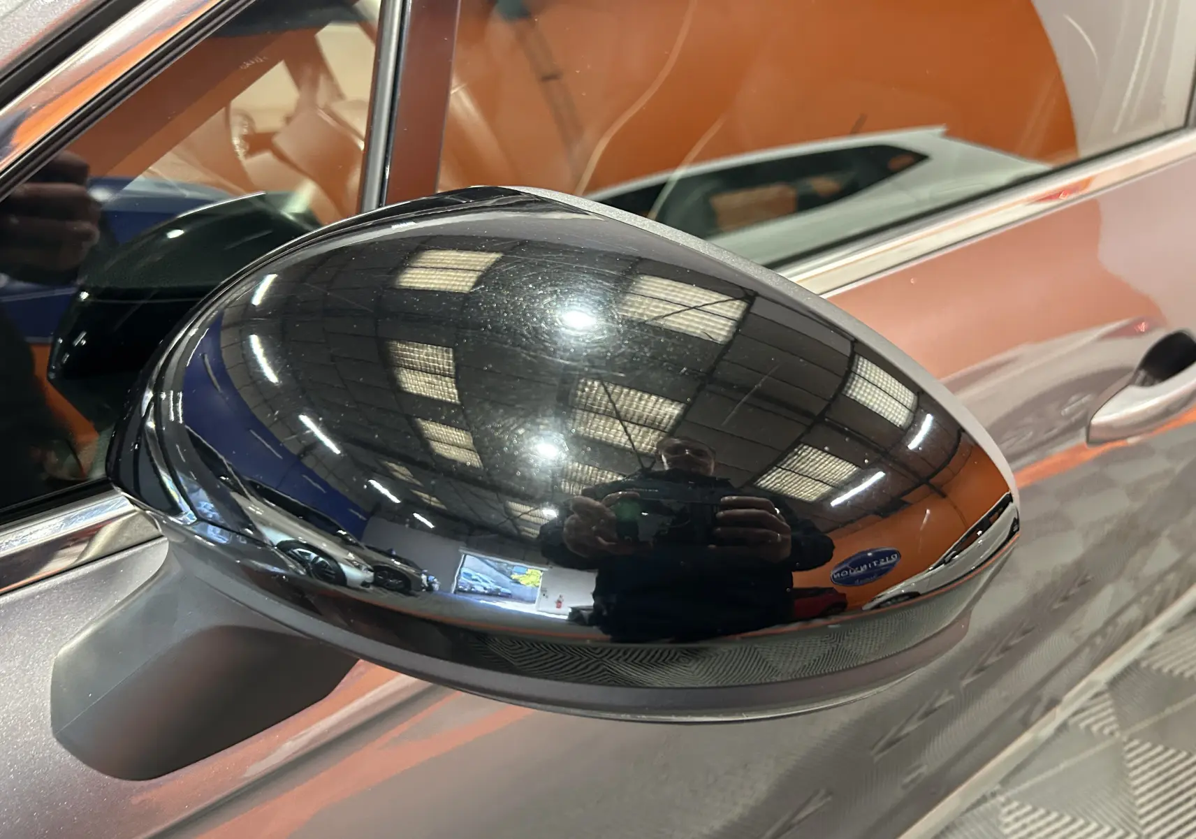 Rétroviseur noir brillant côté gauche d'une Renault Clio V TCe 90 TECHNO gris 2023 avec caméra 360° visible.