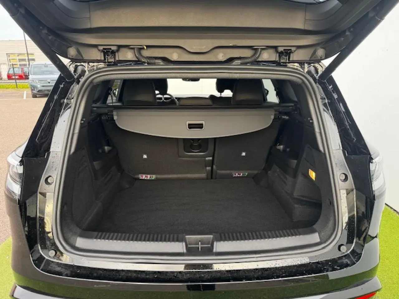 Coffre ouvert vu de l'arrière d'un Renault Espace VI noir étoilé, montrant un espace de chargement spacieux et propre.