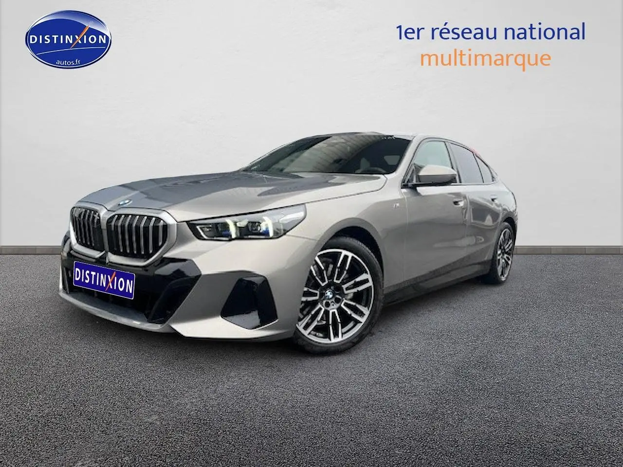 BMW Série 5 gris vue 3/4 avant droit, avec calandre imposante et jantes alliage distinctives.