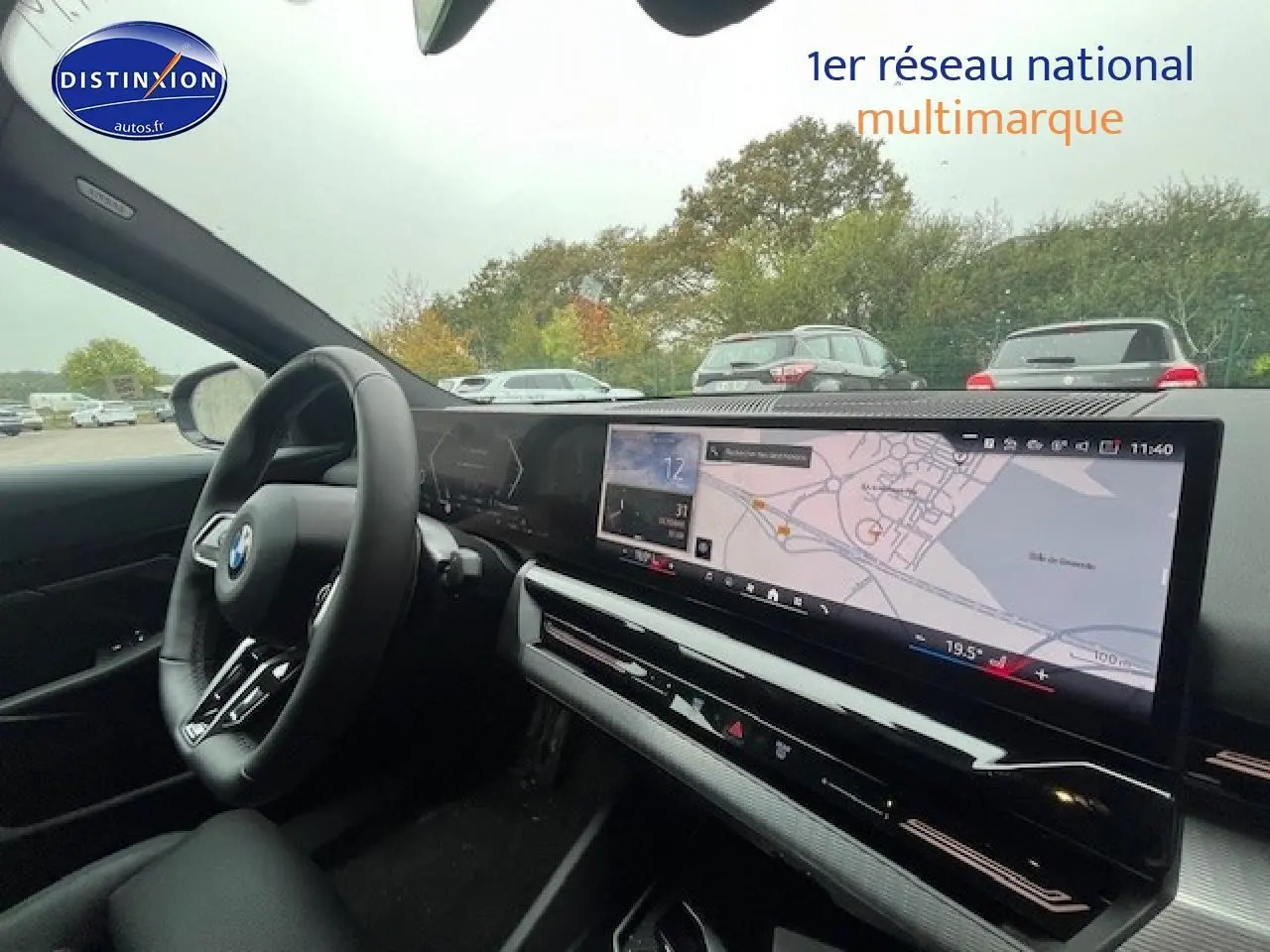 Vue intérieure côté conducteur de la BMW Série 5 gris, avec tableau de bord numérique et écran tactile large affichant la navigation.