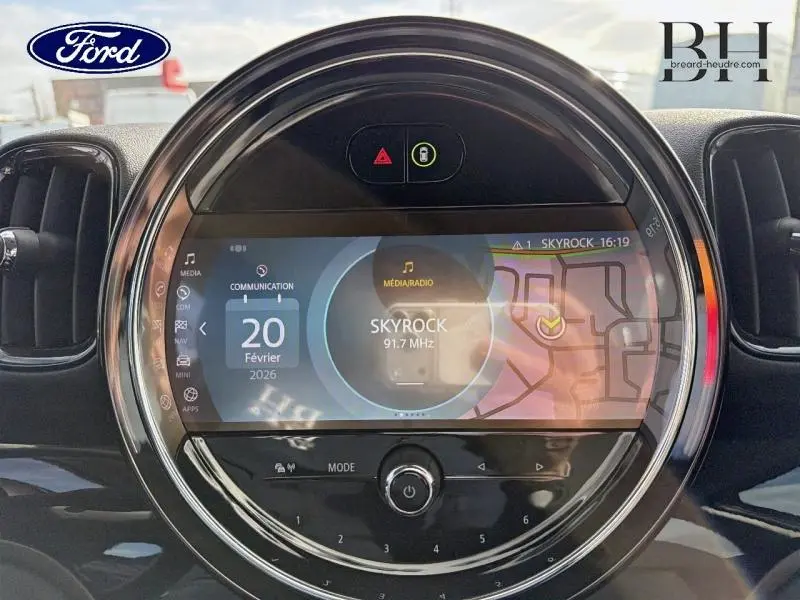 Vue rapprochée de l'écran tactile central rond du MINI Countryman Melting Silver III, affichant la radio Skyrock.