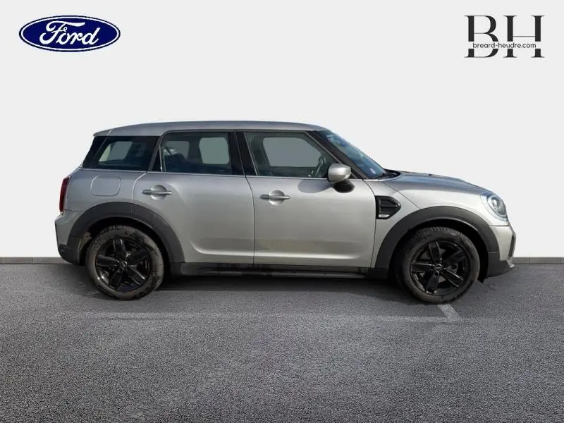 Vue de profil côté gauche d'une MINI COUNTRYMAN Cooper 2023 en Melting Silver III avec jantes noires et toit noir.