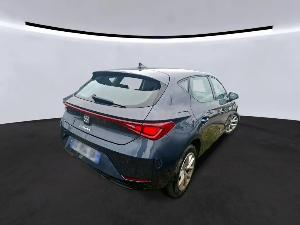 Vue 3/4 arrière droite d'une SEAT Leon gris métallisé 5 portes, avec feux arrière LED et toit avec antenne requin.