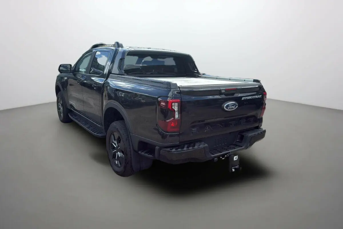 Ford Ranger 2.3 PHEV noir agate vu 3/4 arrière droit avec benne couverte et attelage visible.
