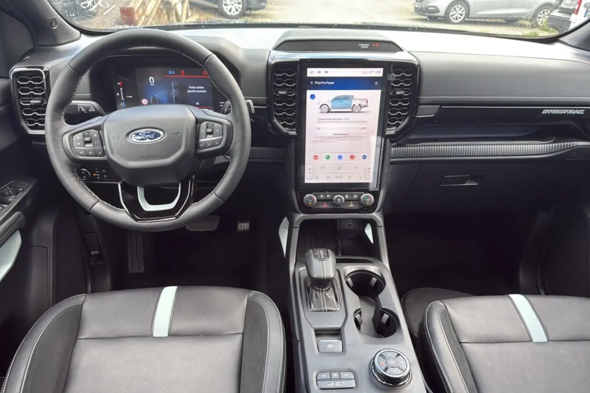 Vue intérieure avant du Ford Ranger 2.3 PHEV noir agate, volant cuir multifonctions et écran tactile vertical central.