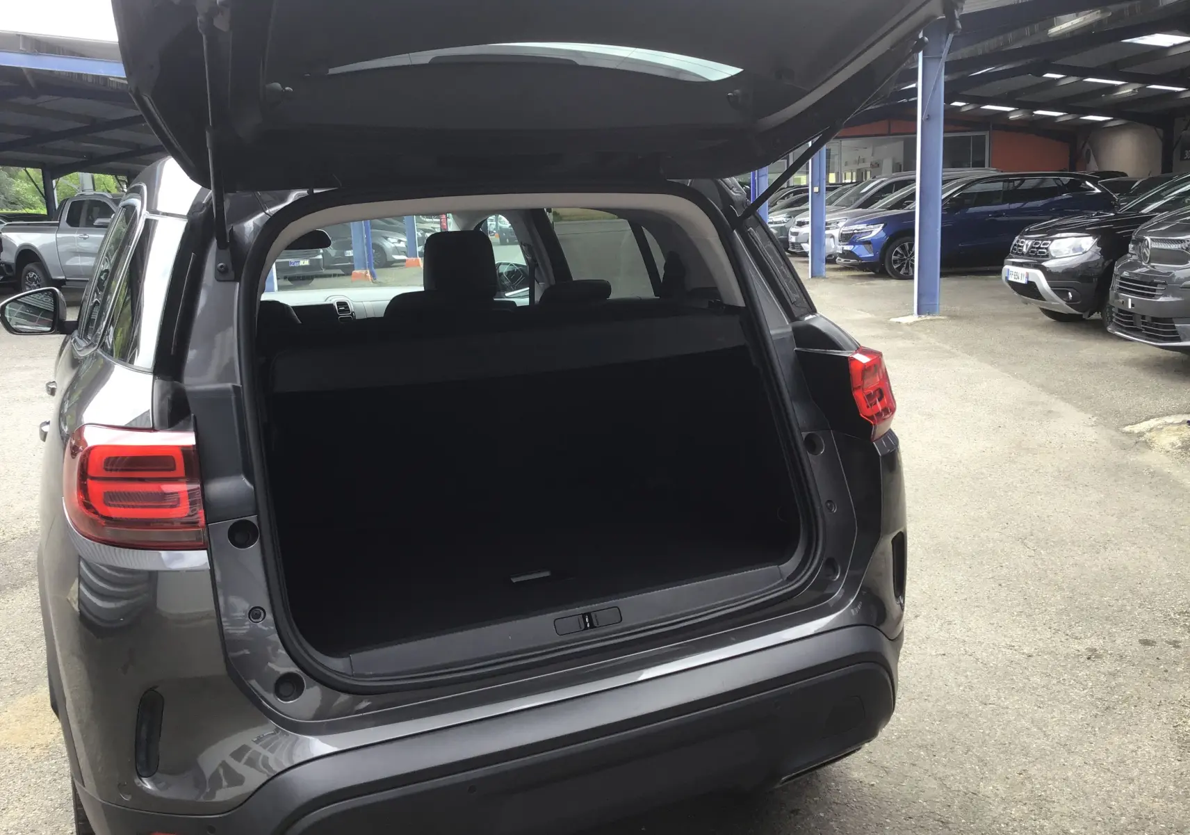 Vue arrière ouverte du Citroën C5 Aircross gris platinium, mettant en valeur le coffre spacieux et les feux arrière LED.