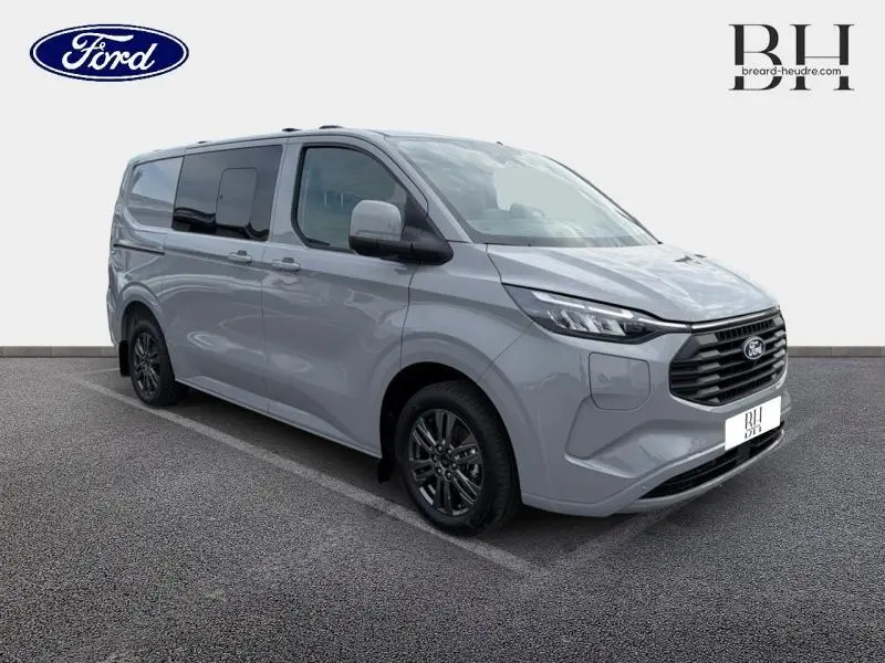 Vue 3/4 avant droit du Ford Transit Custom Fourgon gris Matter Spéciale avec jantes alu gris carbone et vitres latérales surteintées.