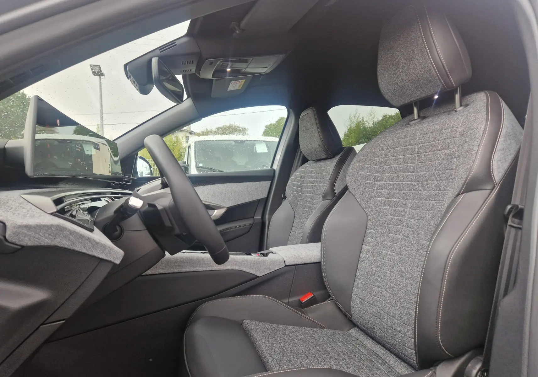 Vue intérieure côté conducteur du Peugeot 3008 2025, sièges tissu et cuir gris avec écran panoramique 21 pouces.