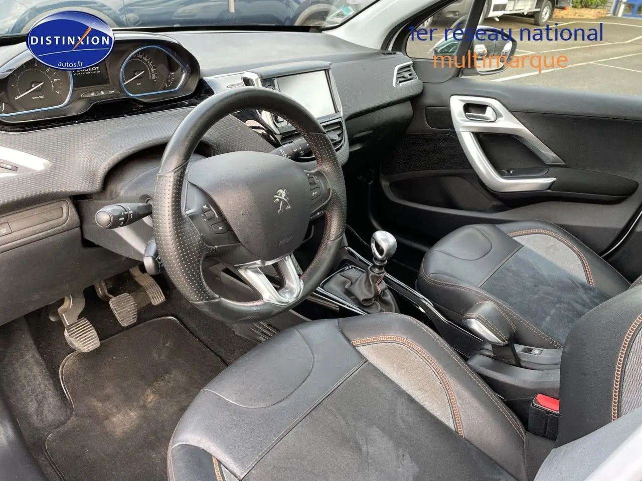 Intérieur de la Peugeot 2008 blanc vue côté conducteur, volant cuir perforé et levier de vitesse manuel visibles.
