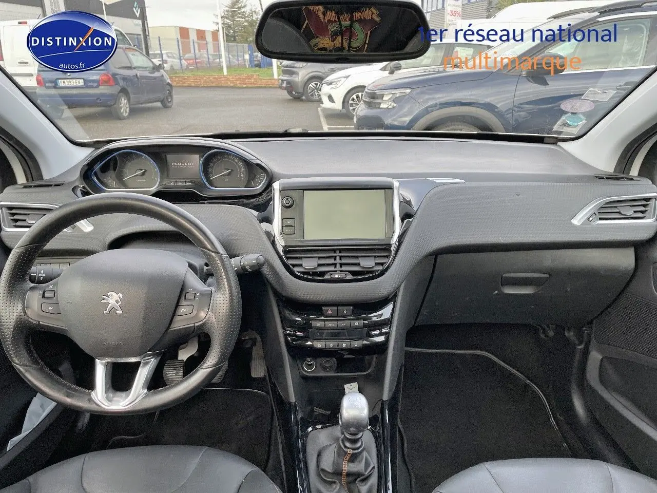 Vue intérieure frontale du tableau de bord noir du Peugeot 2008 blanc avec volant multifonction et écran central tactile.