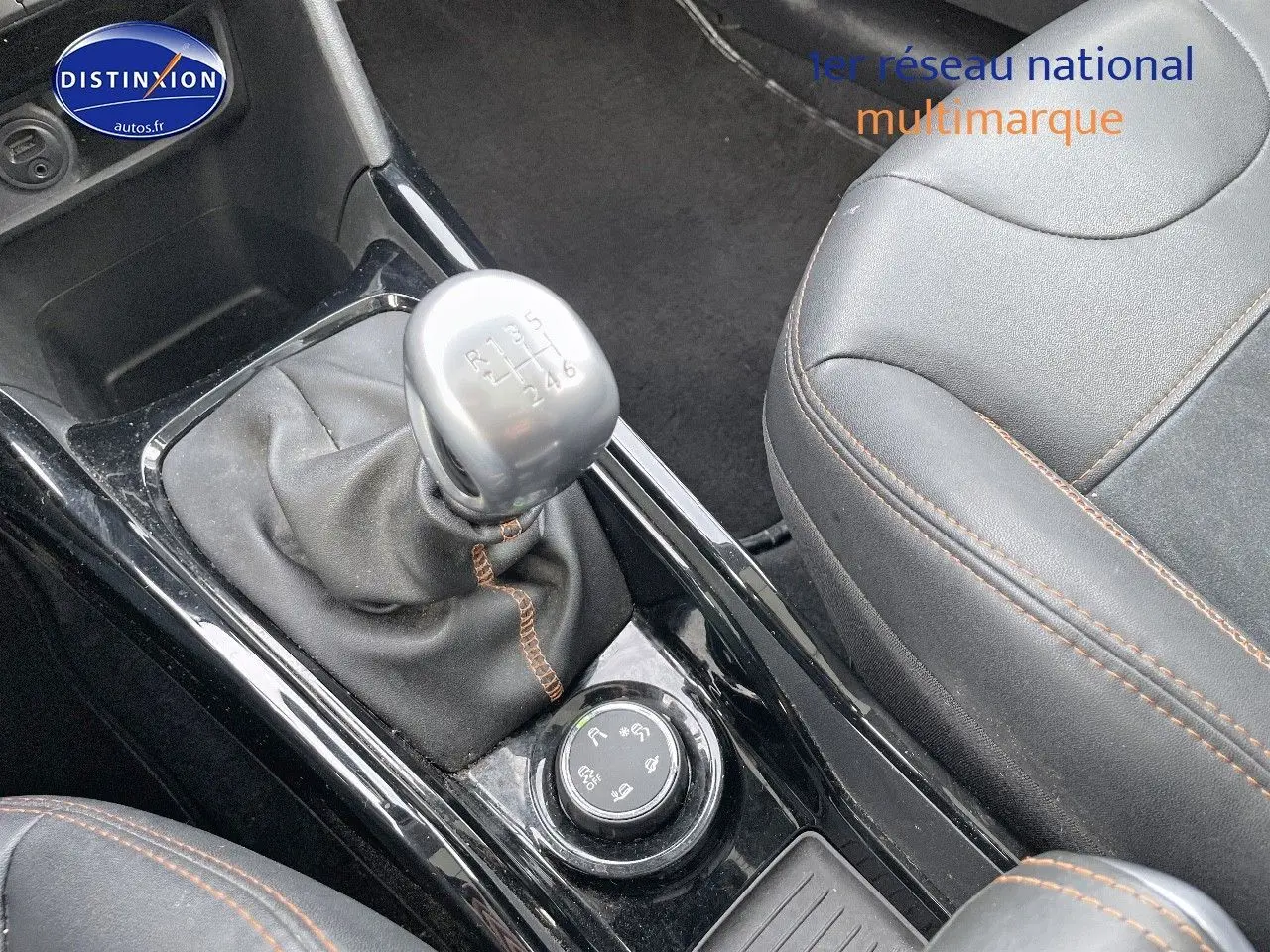 Gros plan sur la console centrale noire du Peugeot 2008 blanc de 2016, avec levier de vitesse manuel et siège cuir noir.