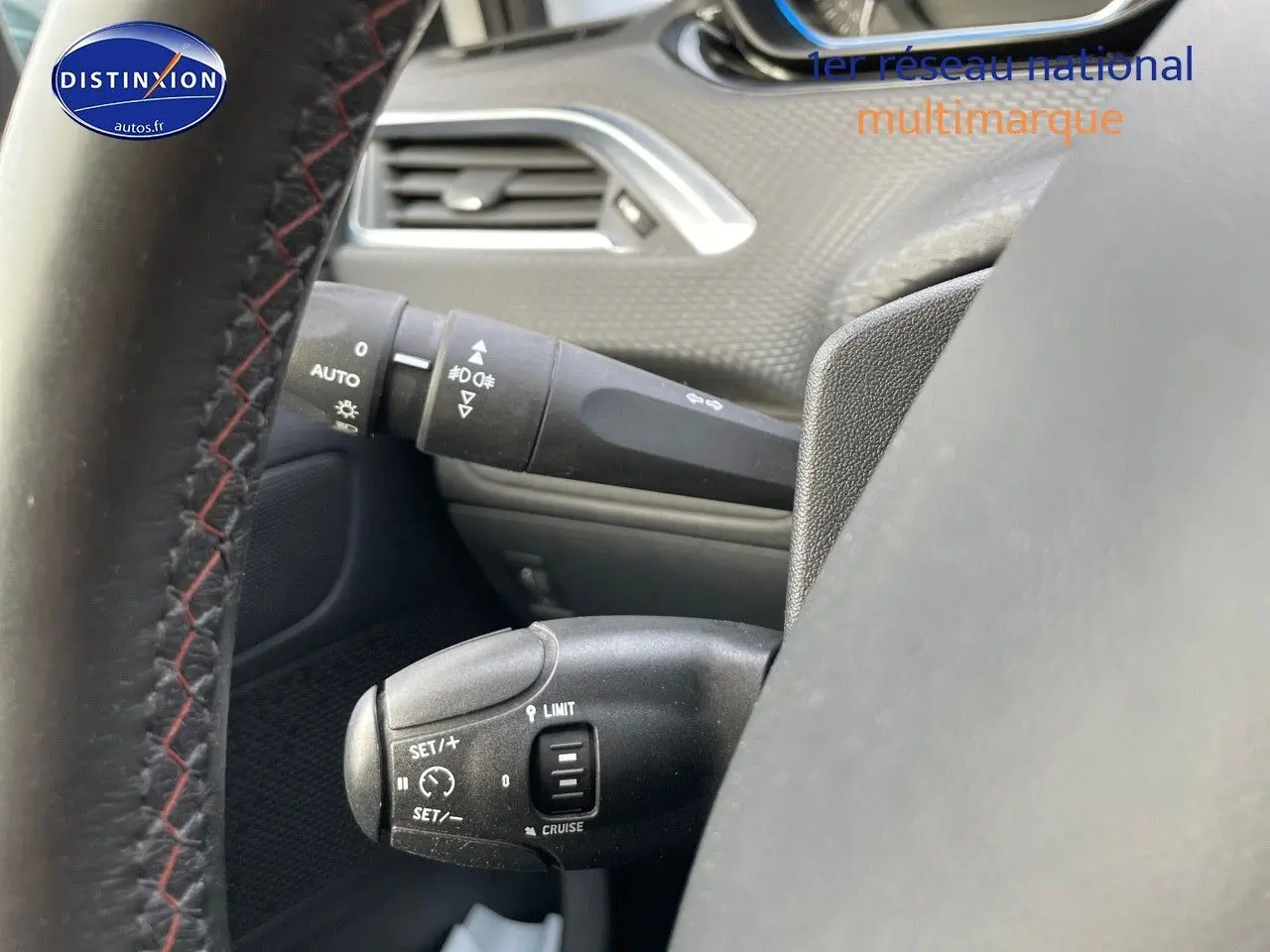 Vue rapprochée du volant côté gauche d'un Peugeot 2008 blanc, mettant en valeur les commandes de régulateur de vitesse.