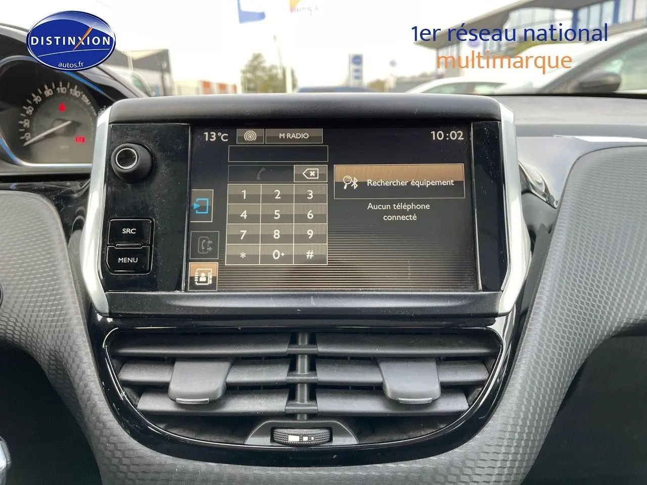 Écran tactile central du tableau de bord d'une Peugeot 2008 blanc, avec commandes et affichage radio visible.