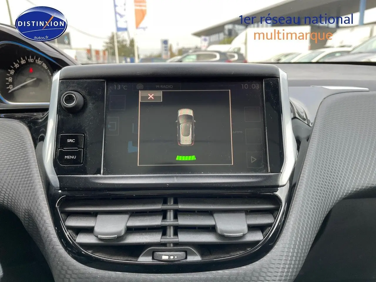 Vue rapprochée du tableau de bord de la Peugeot 2008 blanc, affichant l'écran central avec capteurs de recul actifs.