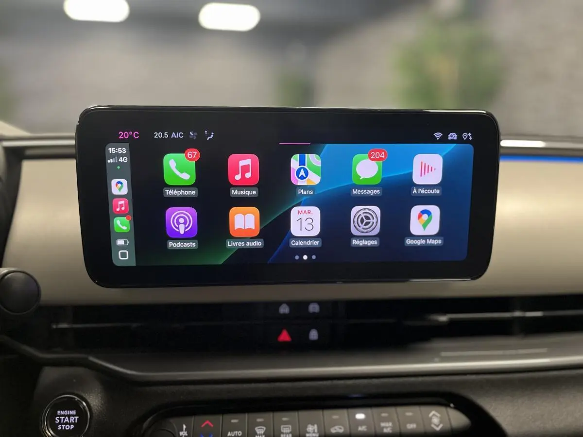Écran tactile central affichant Apple CarPlay dans l'habitacle ivoire du Fiat 600 hybride noir 2024.