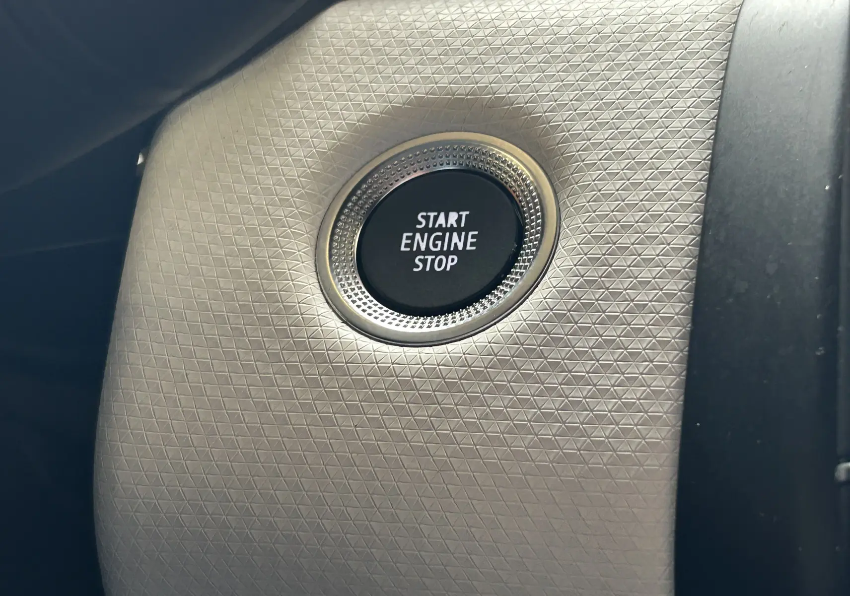 Gros plan sur le bouton Start Engine Stop entouré d'une finition texturée à l'intérieur de la Renault Clio V rouge 2023.